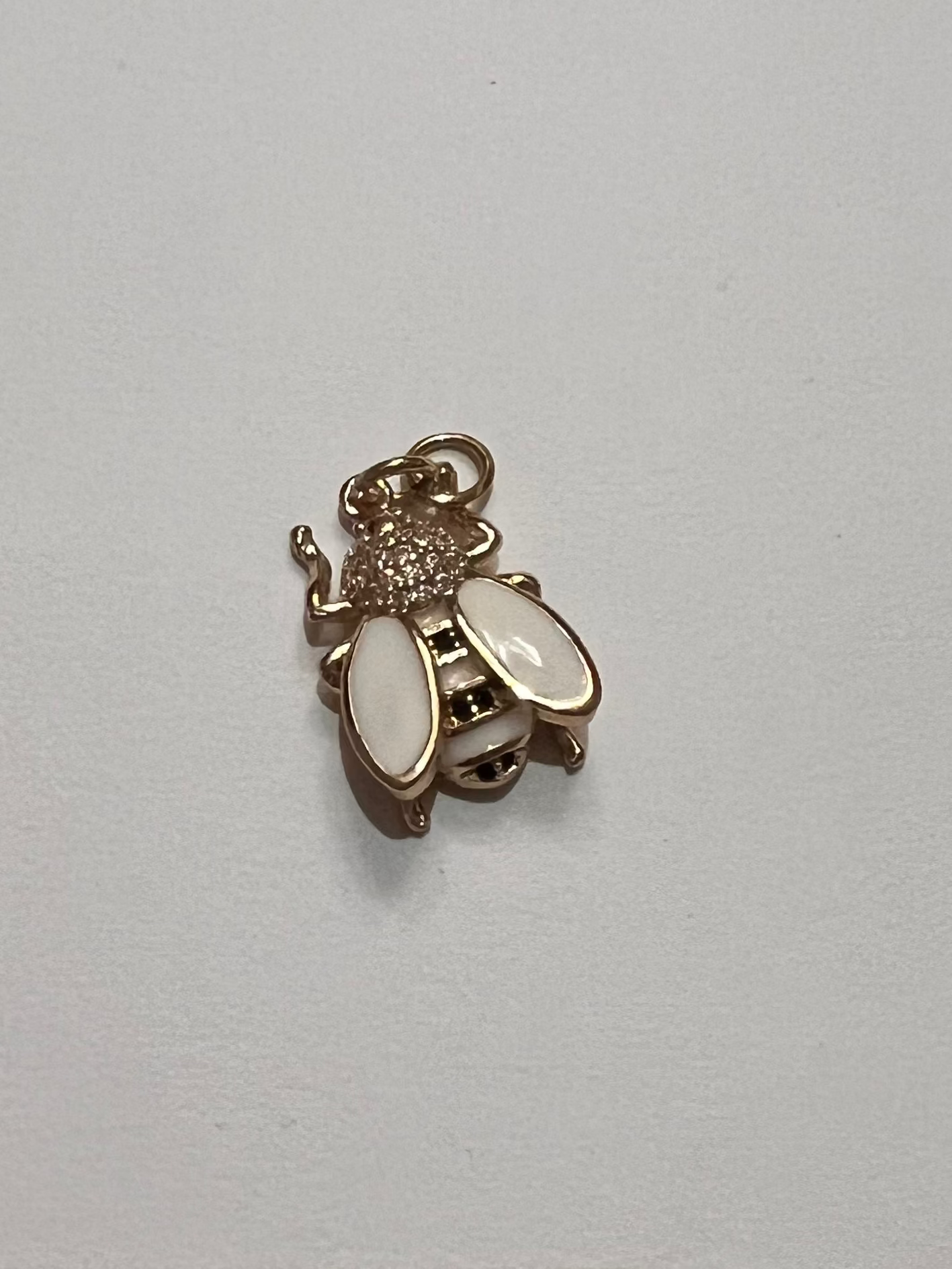 Small gold and black bee charm on a white background