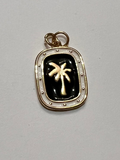 Small pendant with palm tree design on a plain background