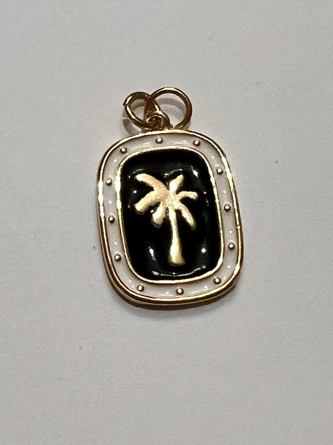 Small pendant with palm tree design on a plain background