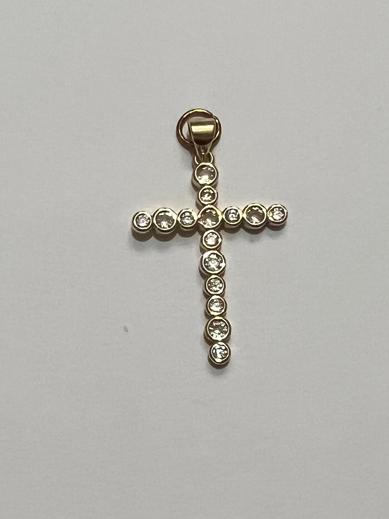  Cross pendant with embedded stones on a light gray background