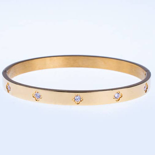 Gold bracelet with small diamonds on a light gray background