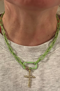 Person wearing a green chain necklace with a gold cross pendant.