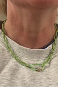 Person wearing a green chain necklace with a neutral background