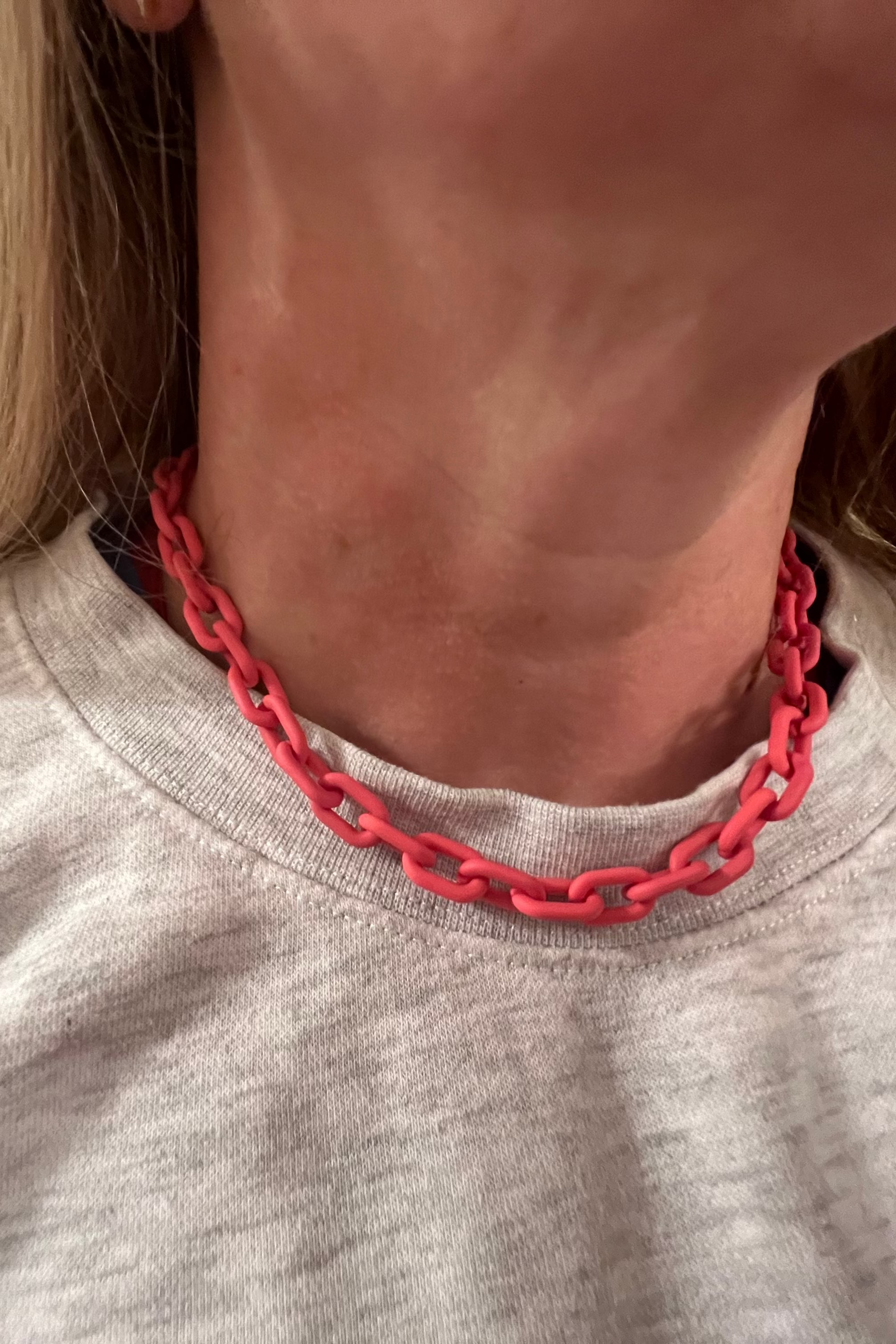 Person wearing a pinkchain necklace on a plain background