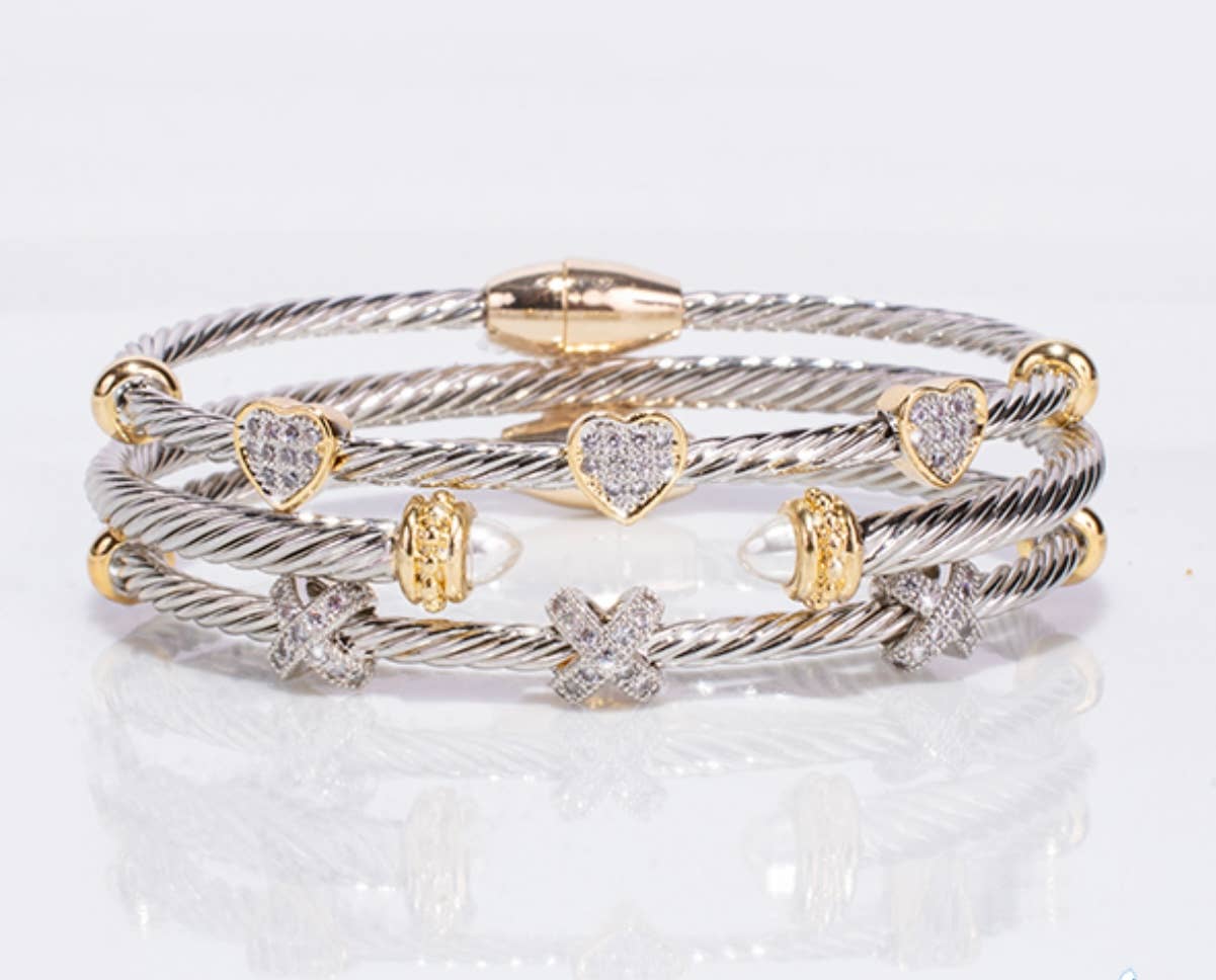 Stack of silver and gold bracelets with heart and star designs on a white background