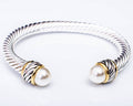Silver and gold bracelet with pearl beads on a light gray background