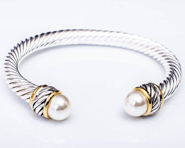Silver and gold bracelet with pearl beads on a light gray background