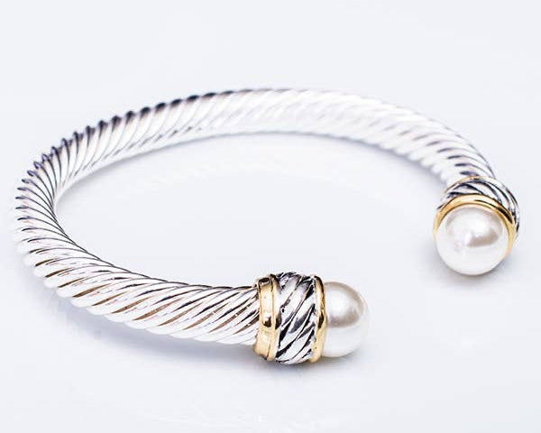 Silver and gold bracelet with pearls on a white background