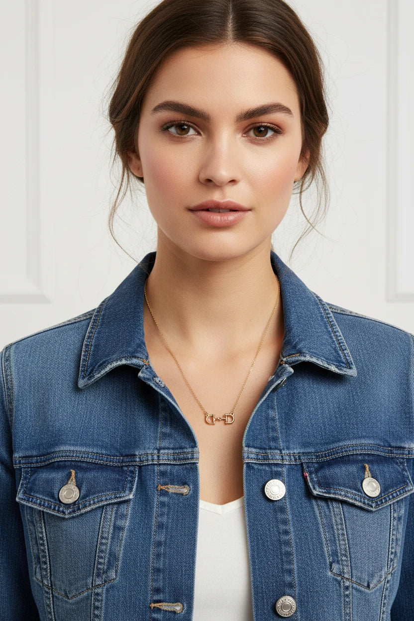 Gold necklace with a horse bit pendant on a white background