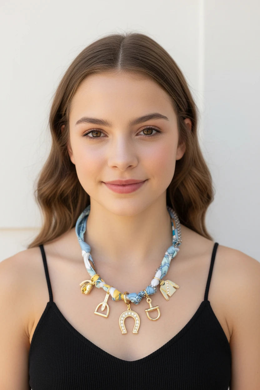 Scarf necklace with gold charms on a white background