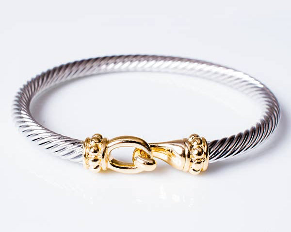 Silver bracelet with a gold clasp on a white background